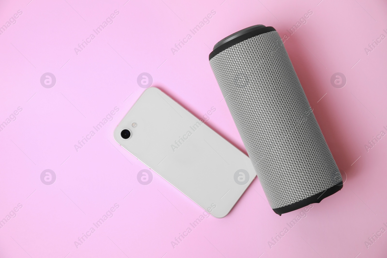 Photo of Portable bluetooth speaker and smartphone on pink background, flat lay with space for text. Audio equipment