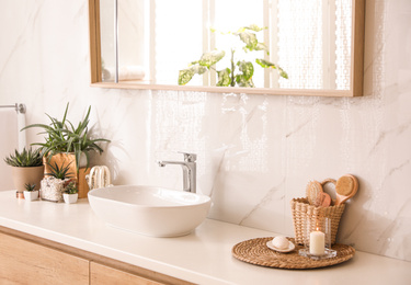 Stylish bathroom interior with countertop, mirror and houseplants. Design idea