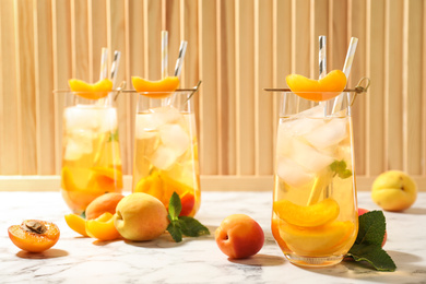 Photo of Delicious refreshing drink with apricot on white marble table