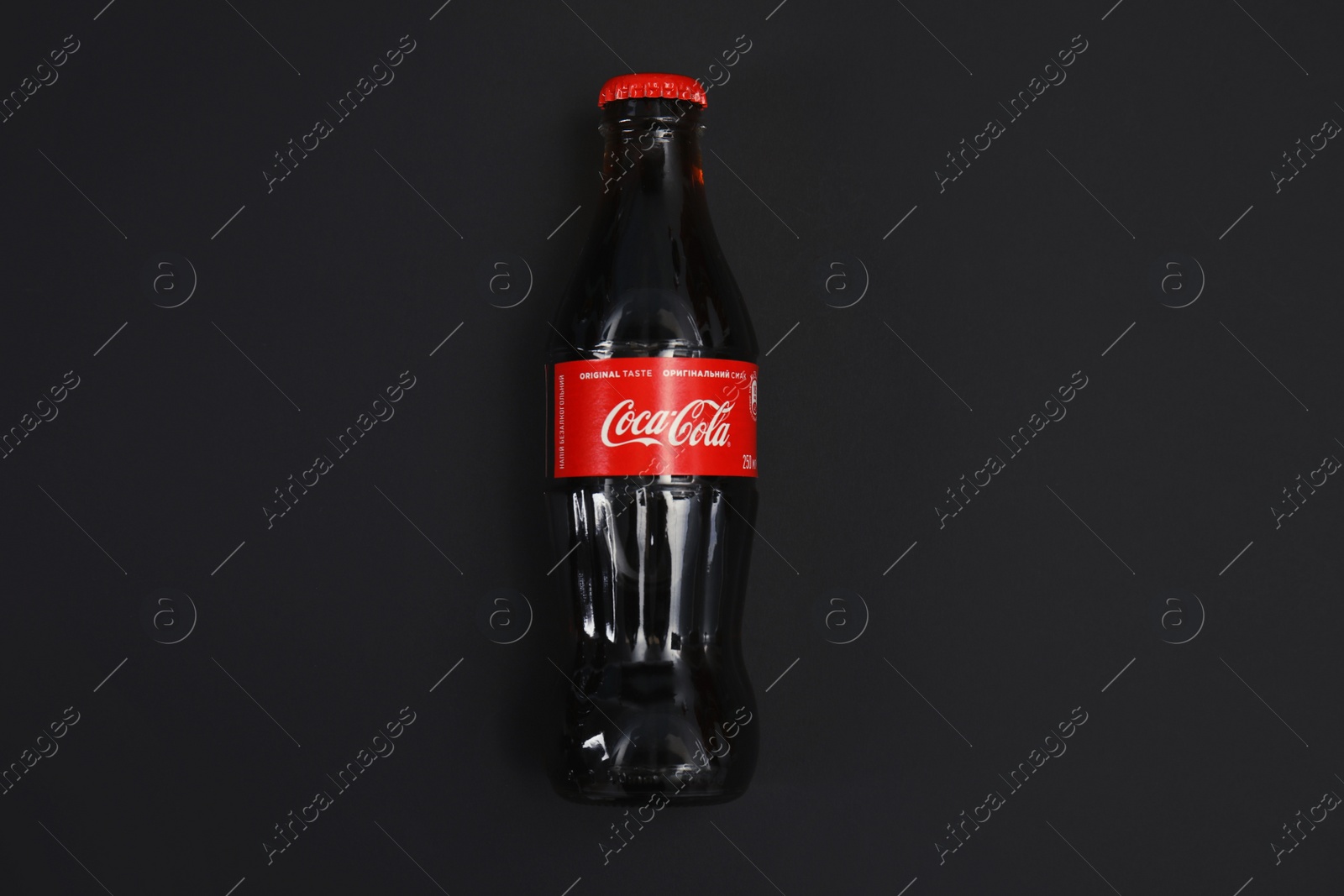 Photo of MYKOLAIV, UKRAINE - NOVEMBER 14, 2018: Bottle of Coca-Cola on black background, top view