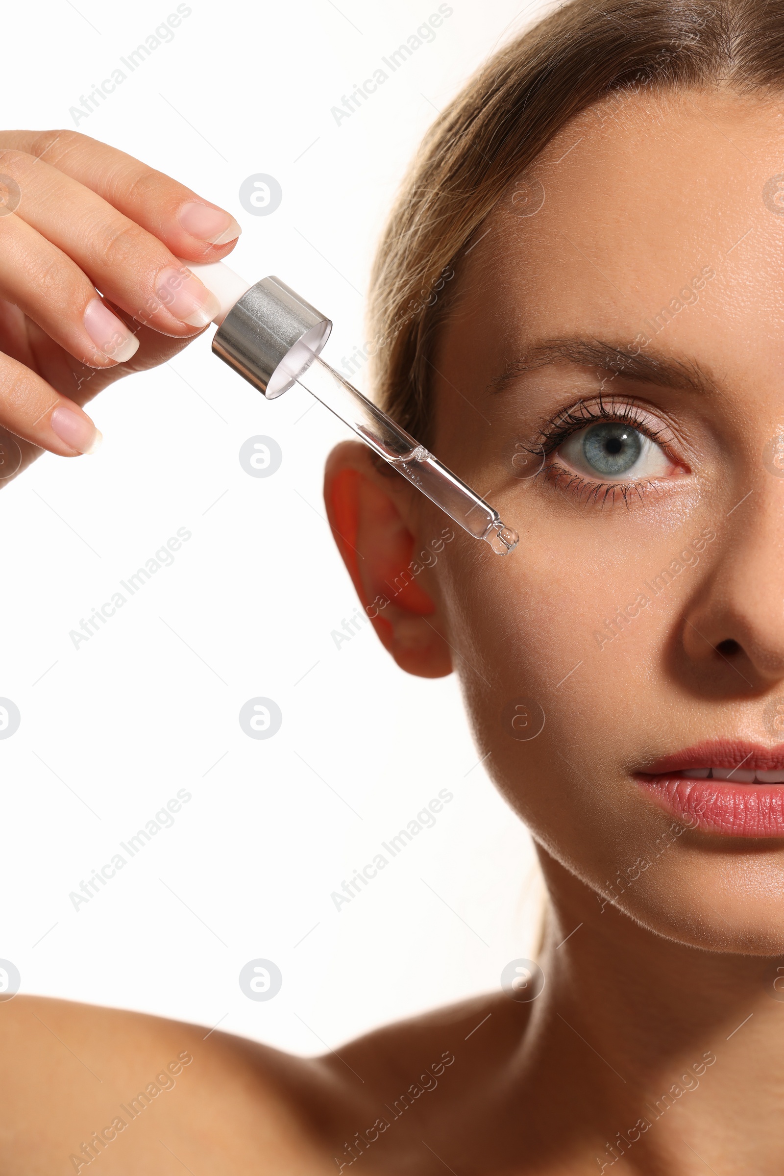 Photo of Woman applying cosmetic serum onto her face on white background, closeup