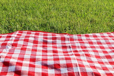 Photo of Checkered picnic tablecloth on fresh green grass outdoors