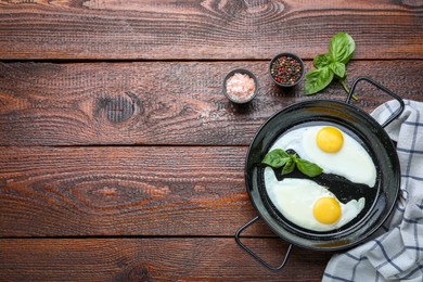 Pan with tasty fried eggs on wooden table, flat lay. Space for text