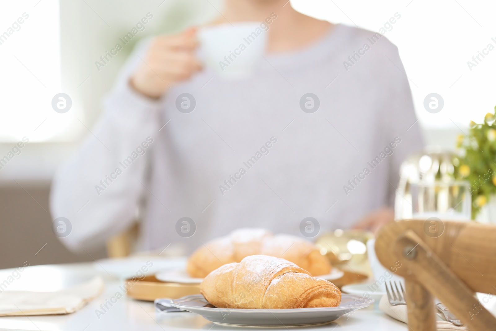 Photo of Tasty breakfast with fresh croissants and blurred woman on background