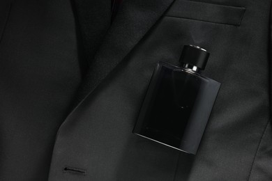 Luxury men's perfume in bottle on black jacket, top view. Space for text