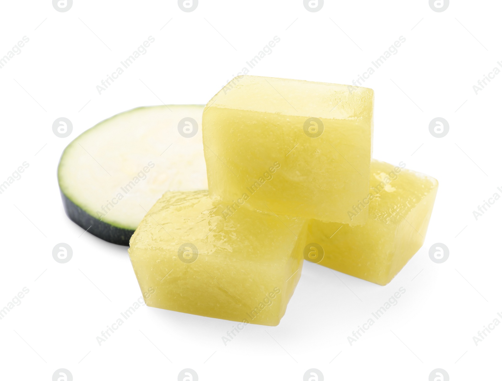 Photo of Frozen zucchini puree cubes and fresh zucchini isolated on white