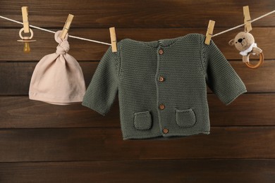 Photo of Baby clothes and accessories hanging on washing line near wooden wall