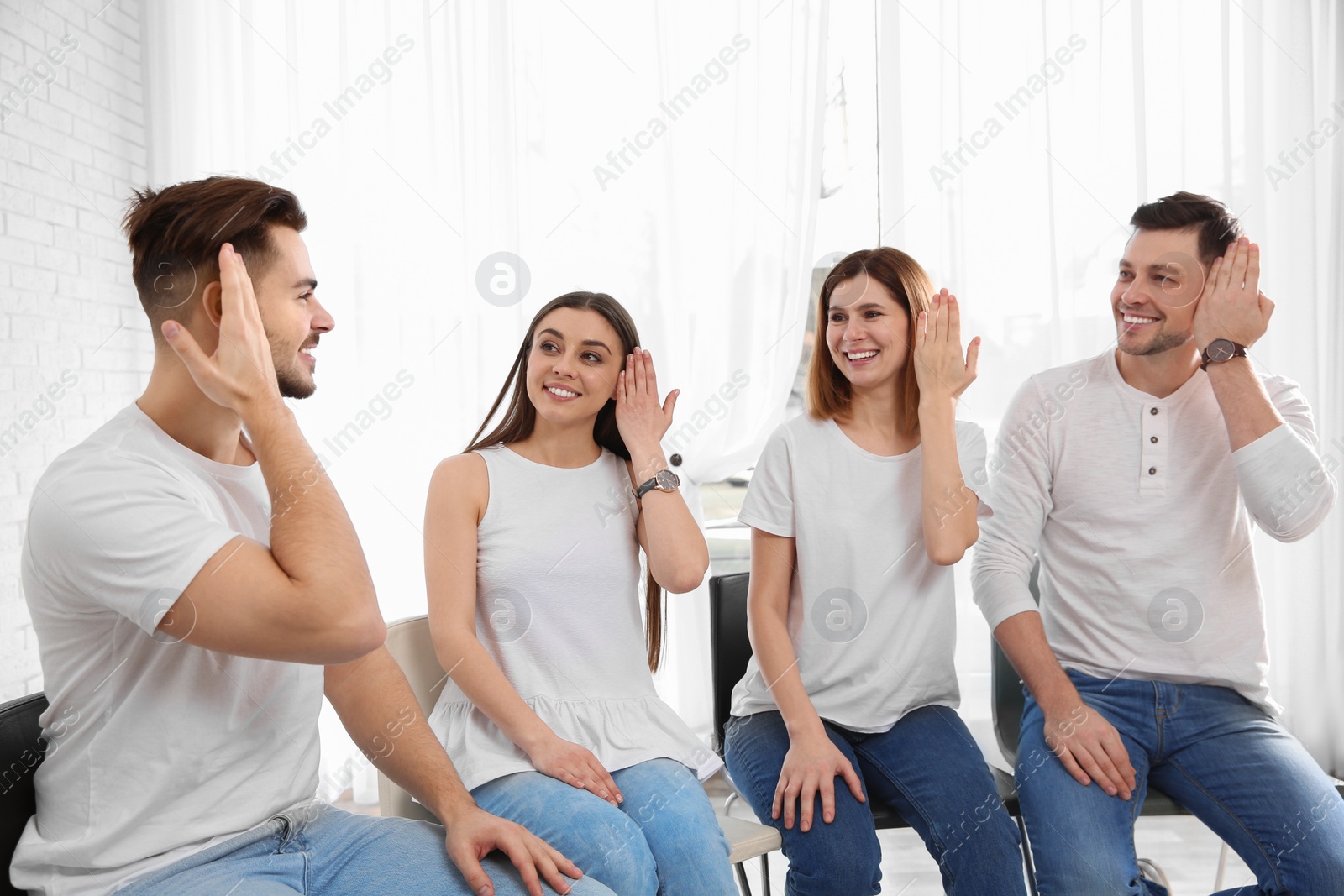 Photo of Group of young people learning sign language with teacher indoors