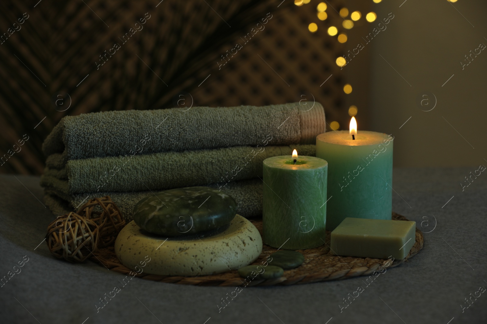 Photo of Spa composition. Burning candles, stones, soap and towels on grey table