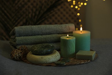 Photo of Spa composition. Burning candles, stones, soap and towels on grey table