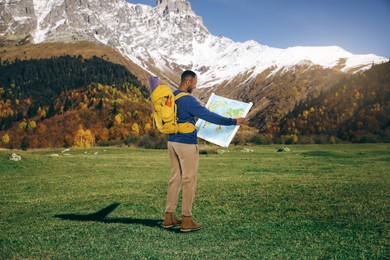 Image of Tourist with backpack and map in mountains
