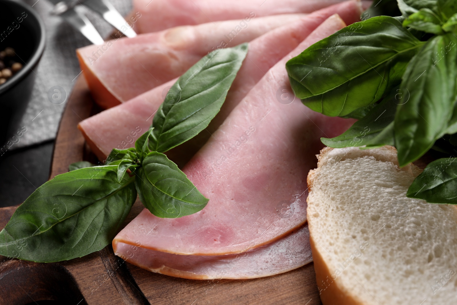 Photo of Tasty ham with basil and bread on table, closeup