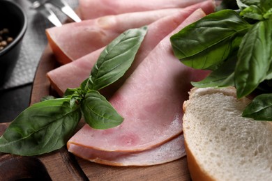 Tasty ham with basil and bread on table, closeup