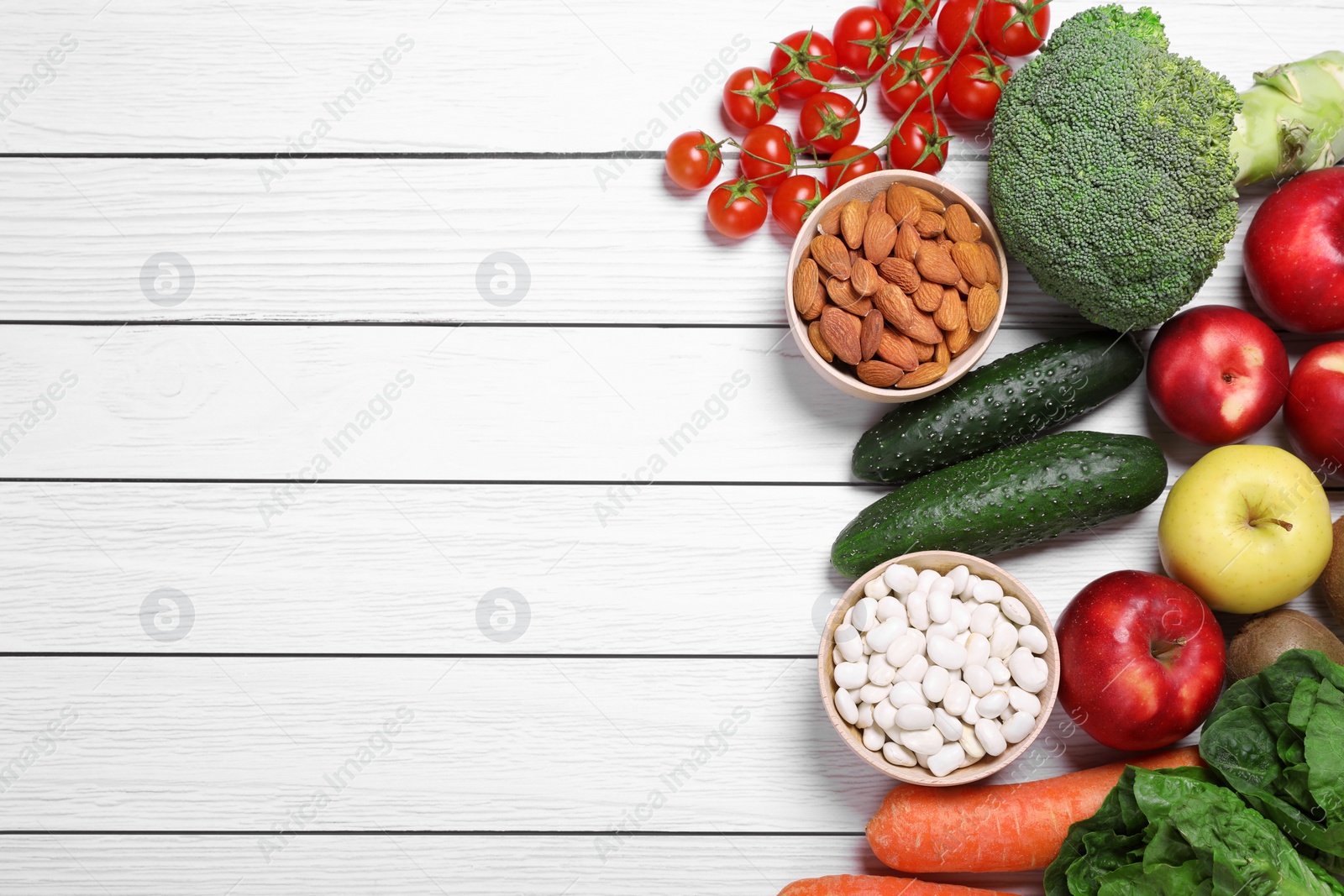 Photo of Almonds, fresh fruits and vegetables on white wooden table, flat lay with space for text. Low glycemic index diet