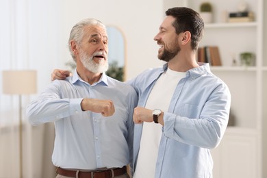 Photo of Happy son and his dad making fist bump at home