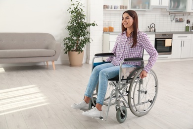 Photo of Young woman sitting in modern wheelchair indoors