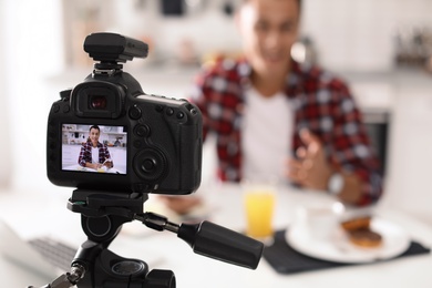 Photo of Food blogger recording video in kitchen, focus on camera display. Space for text