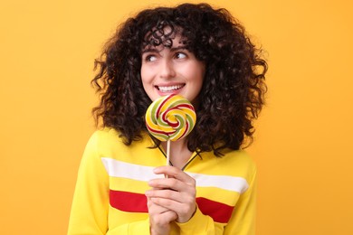 Beautiful woman with lollipop on yellow background
