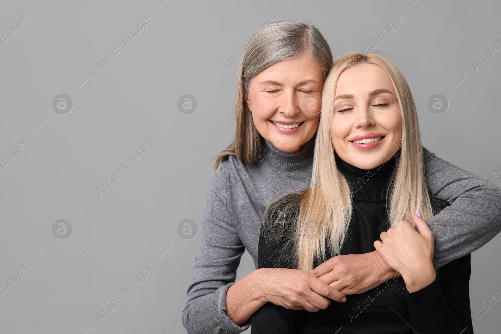 Photo of Family portrait of young woman and her mother on grey background. Space for text