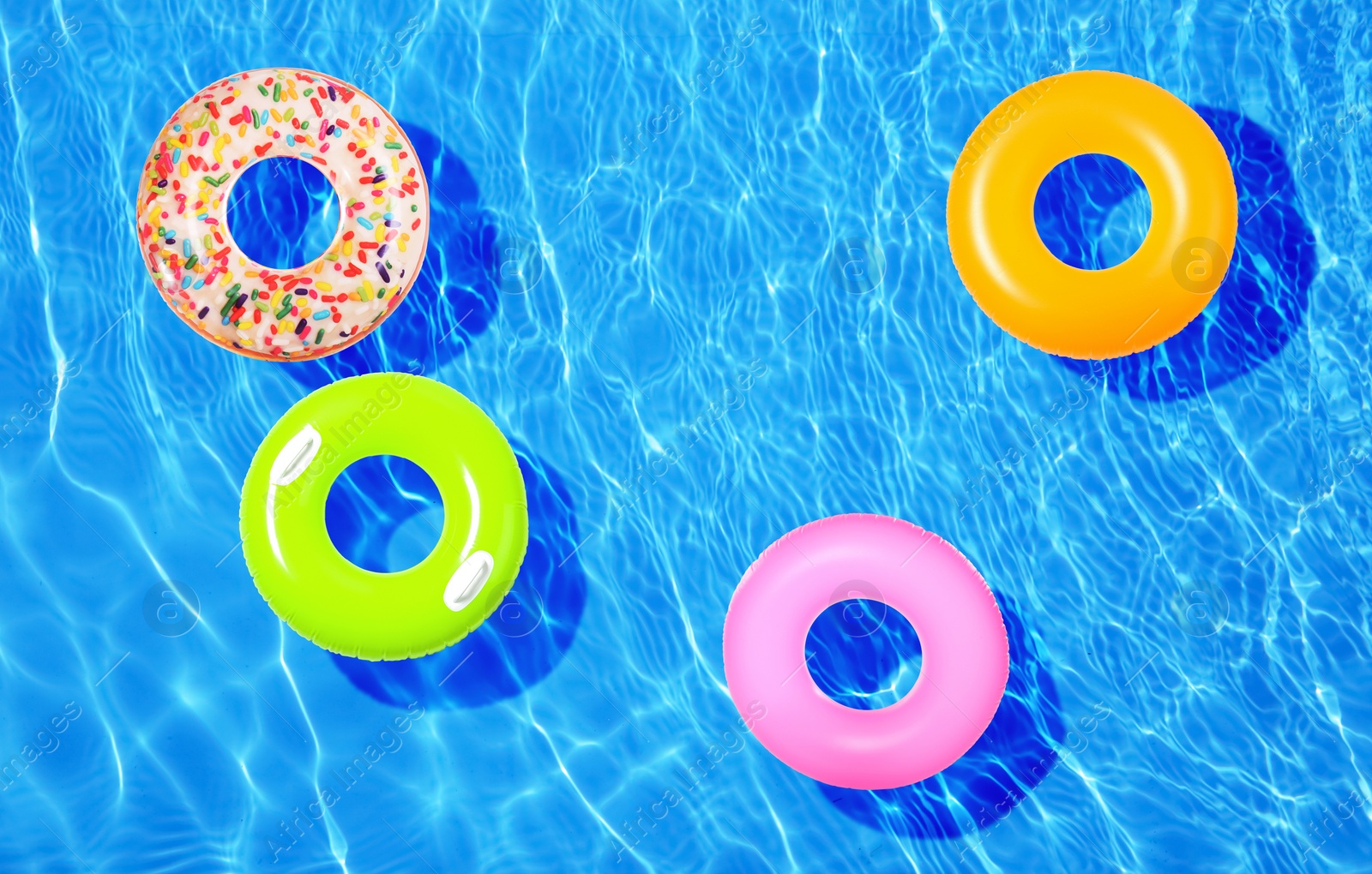 Image of Different inflatable rings floating in swimming pool, top view