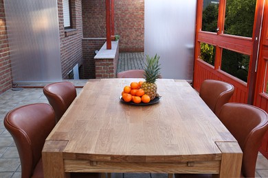 Photo of Wooden table with fruits and stylish chairs on terrace