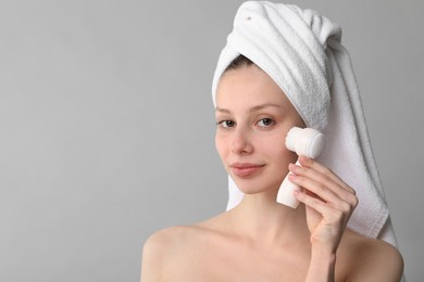 Photo of Washing face. Young woman with cleansing brush on grey background, space for text