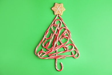 Christmas tree shape made with tasty candy canes on color background