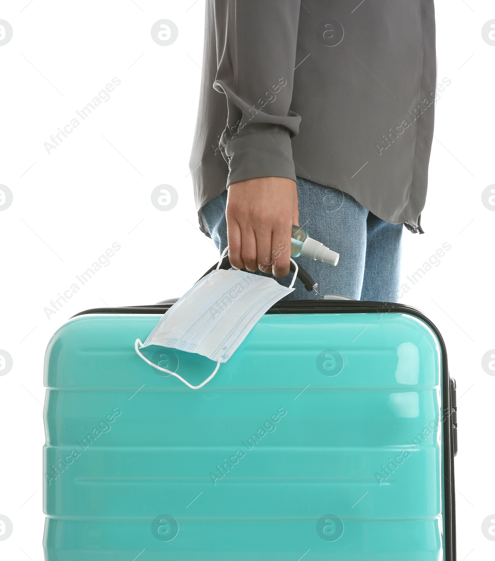 Photo of Woman with suitcase, antiseptic spray and protective mask on white background, closeup. Travelling during coronavirus pandemic