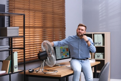 Man enjoying air flow from fan at workplace