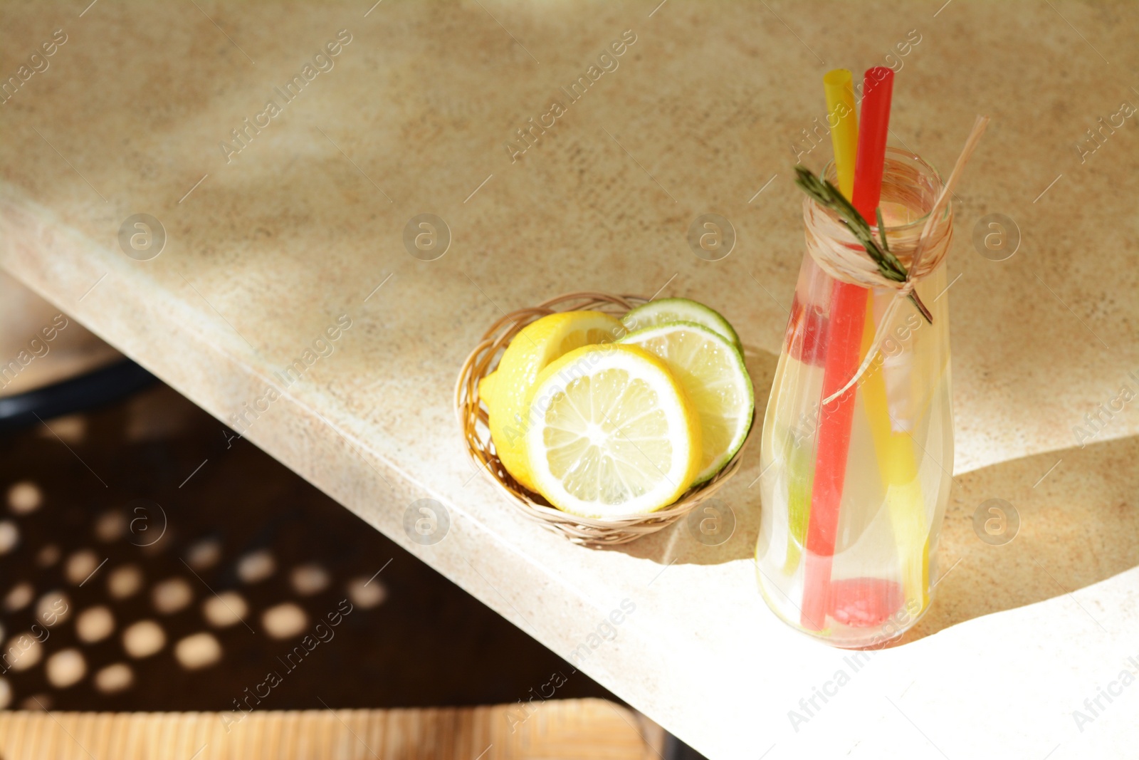 Photo of Refreshing tasty lemonade served in glass bottle and citrus fruits on beige table. Space for text