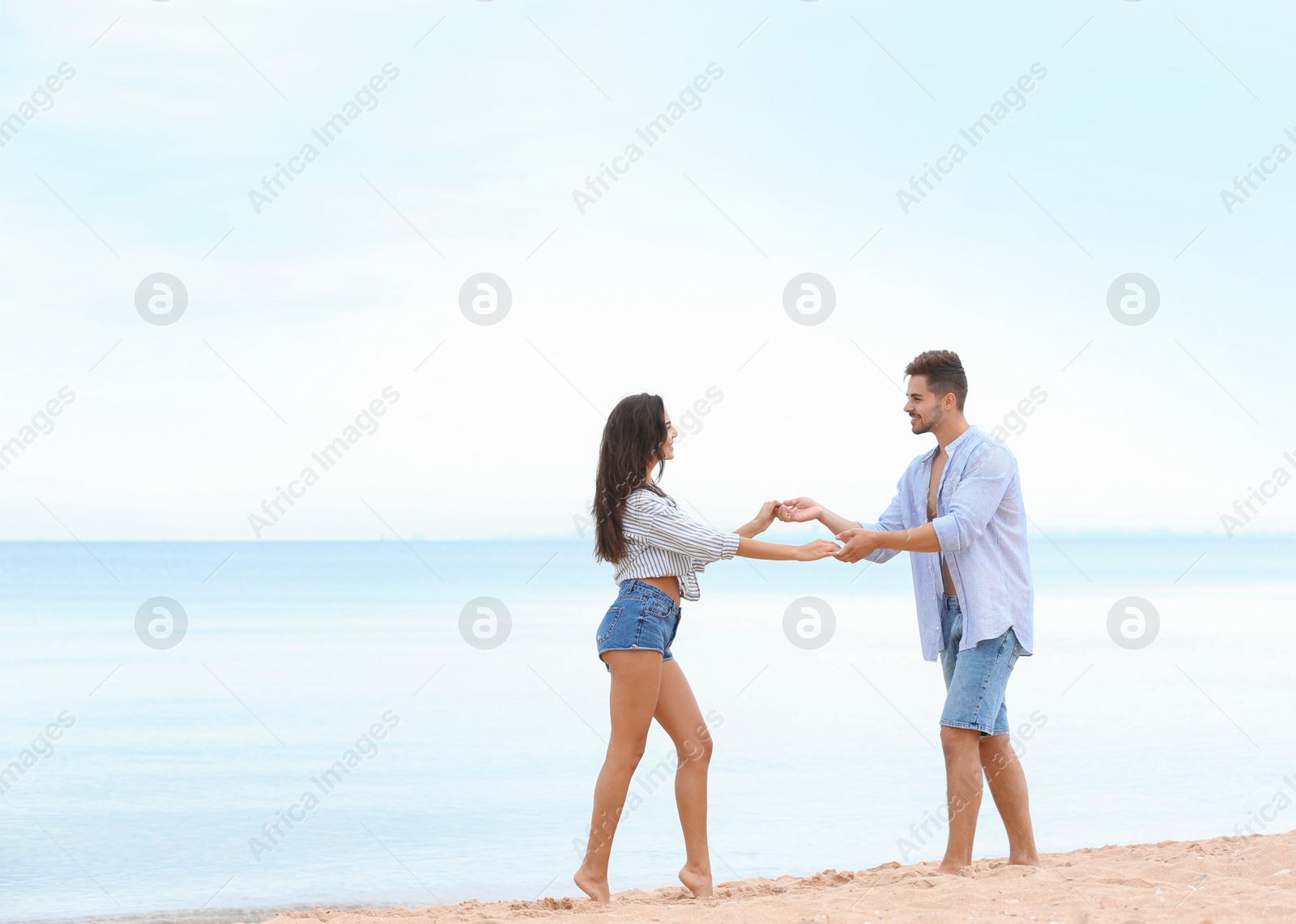 Photo of Happy young couple spending time together on beach near sea