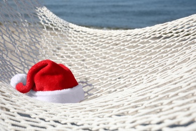 Rope hammock with Santa's hat on beach, closeup. Christmas vacation