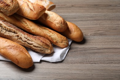 Photo of Different tasty baguettes on wooden table. Space for text