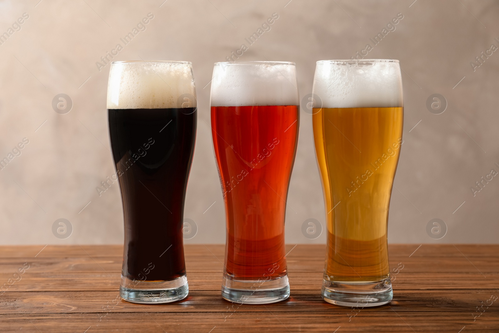 Photo of Glasses with different types of cold tasty beer on wooden table