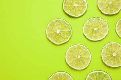 Photo of Fresh juicy lime slices on yellow background, flat lay. Space for text