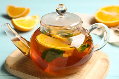 Photo of Hot tea with lemon slices and mint on light blue table, closeup