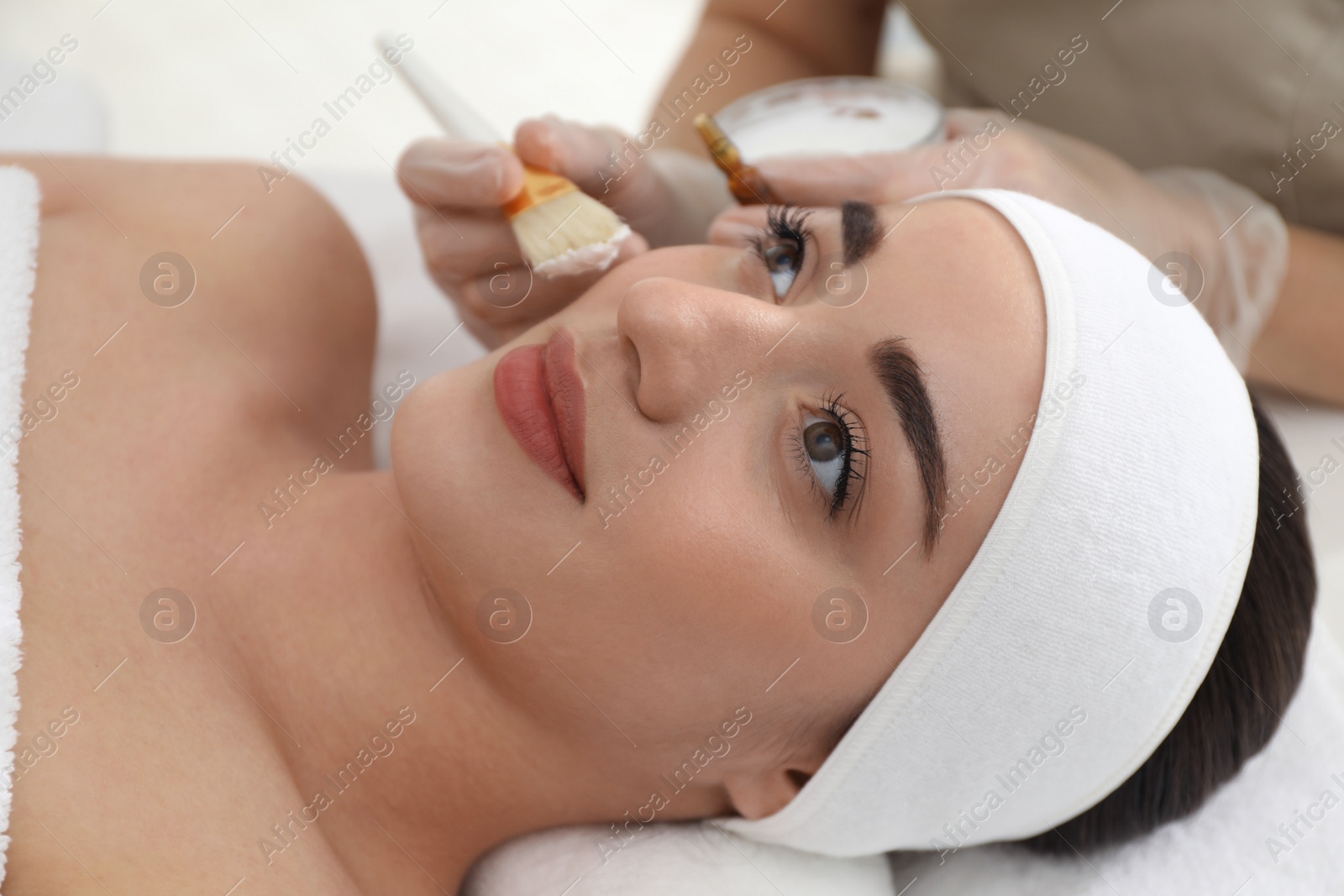 Photo of Young woman during face peeling procedure in salon