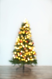 Blurred view of beautiful Christmas tree with fairy lights, indoors