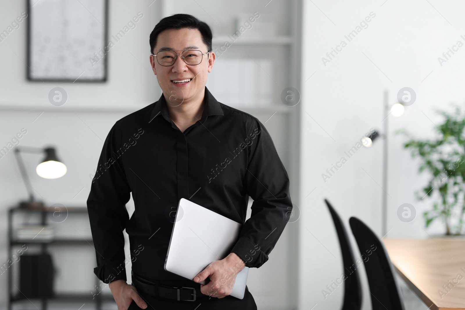 Photo of Portrait of smiling businessman with laptop in office. Space for text