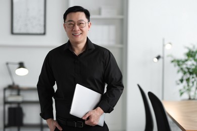 Portrait of smiling businessman with laptop in office. Space for text