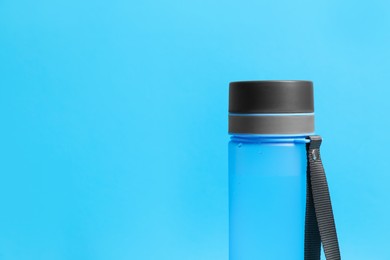 Photo of Stylish bottle on light blue background, space for text