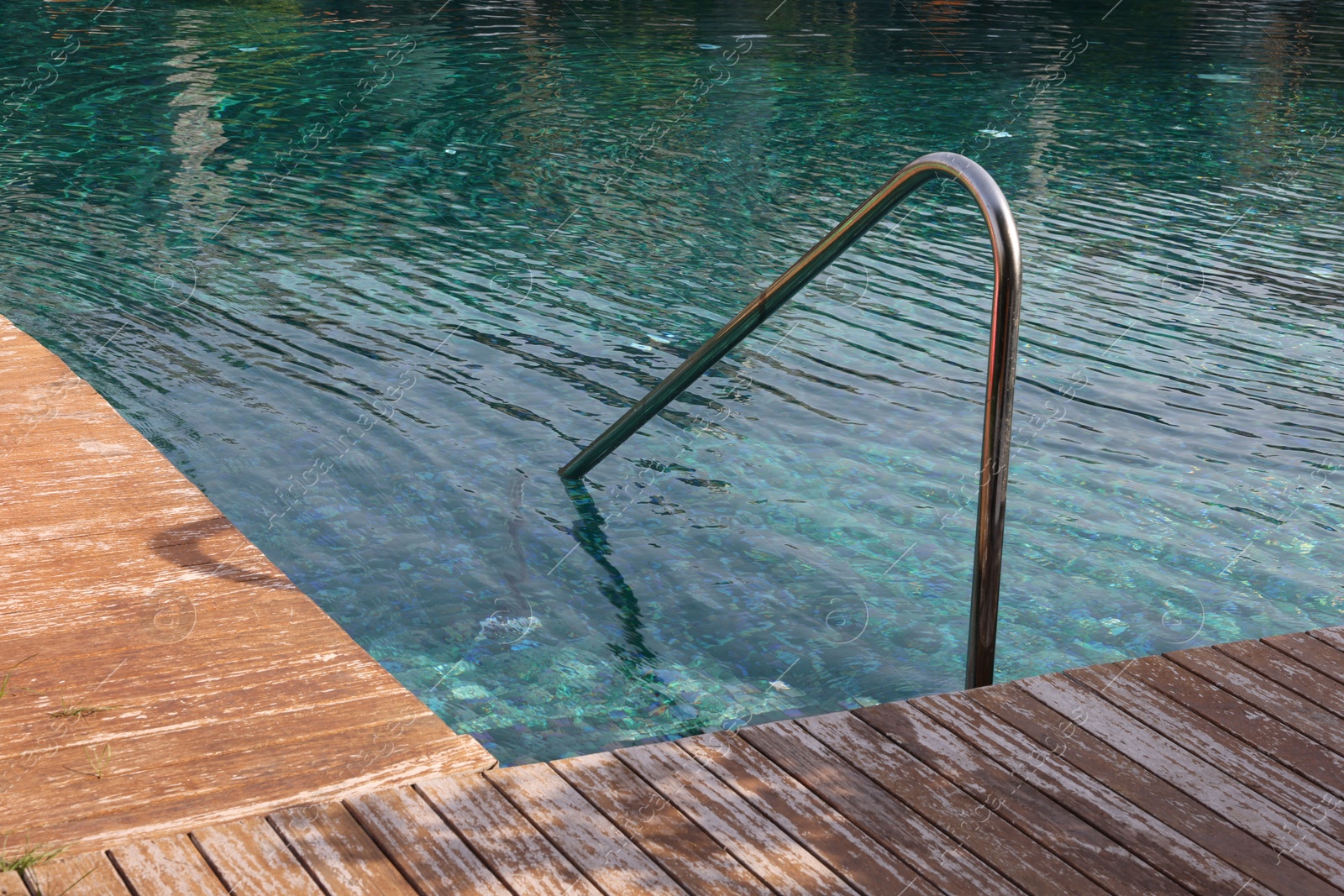 Photo of Swimming pool, metal rail and wooden deck at luxury resort