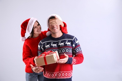 Photo of Woman presenting Christmas gift to her boyfriend on light background