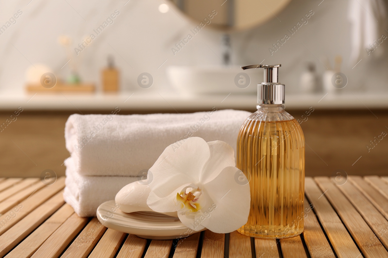 Photo of Composition with liquid soap in glass dispenser on wooden table indoors