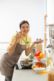 Photo of Young woman cooking tasty soup in kitchen