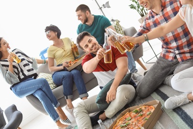 Young people having fun party with delicious pizza indoors