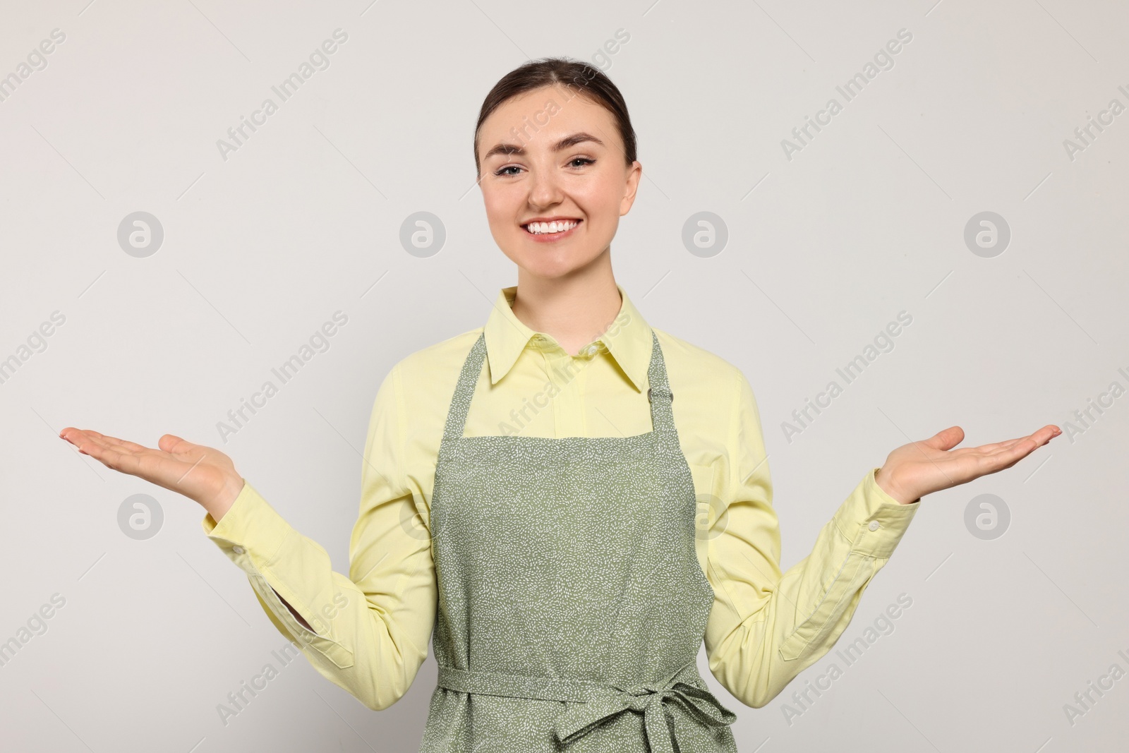 Photo of Beautiful young woman in clean apron with pattern on light grey background