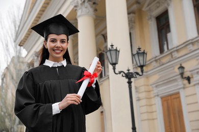 Photo of Happy student with diploma after graduation ceremony outdoors. Space for text