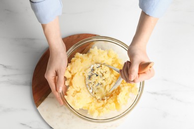 Photo of Woman making mashed potato at white marble table, top view