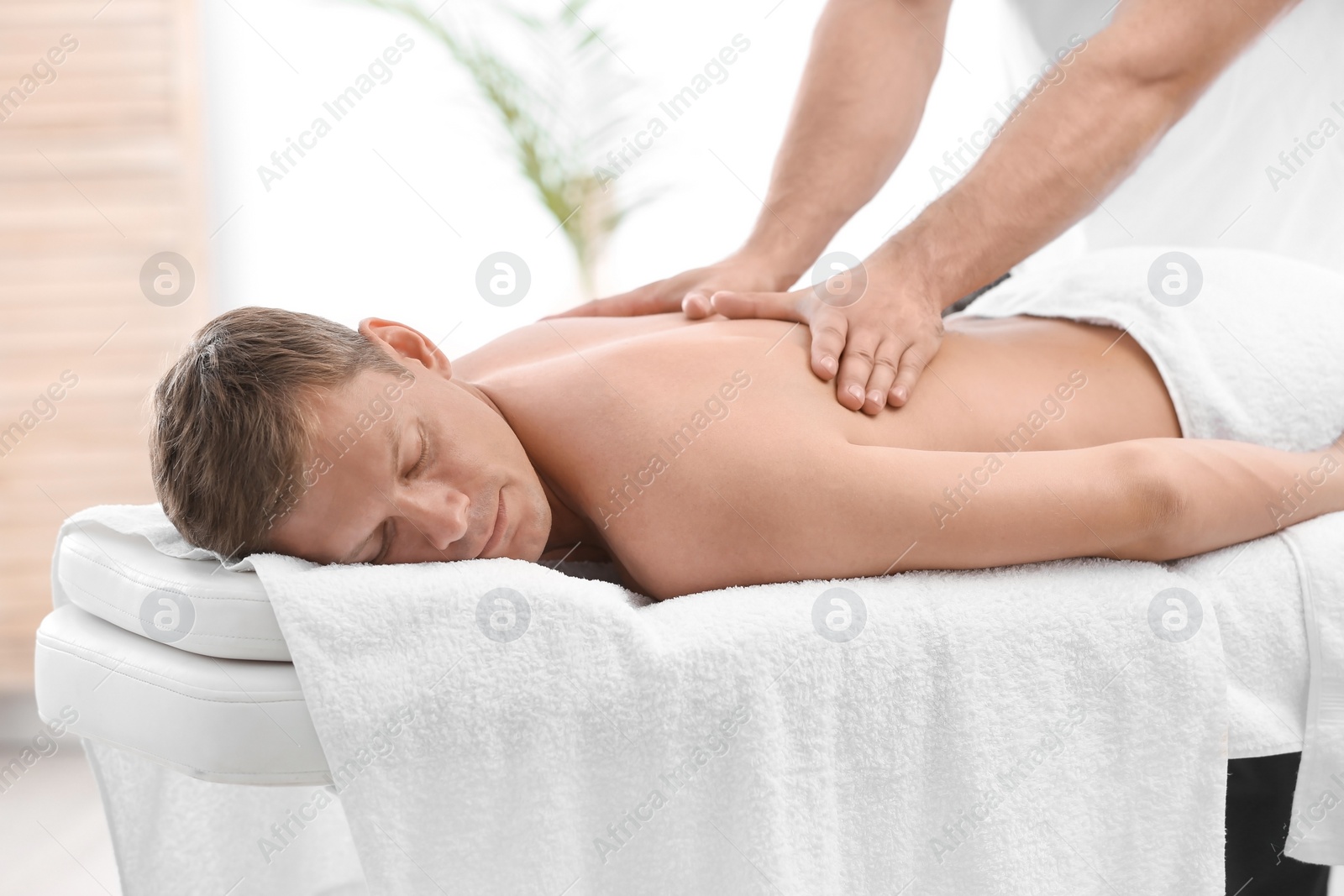 Photo of Relaxed man receiving back massage in wellness center